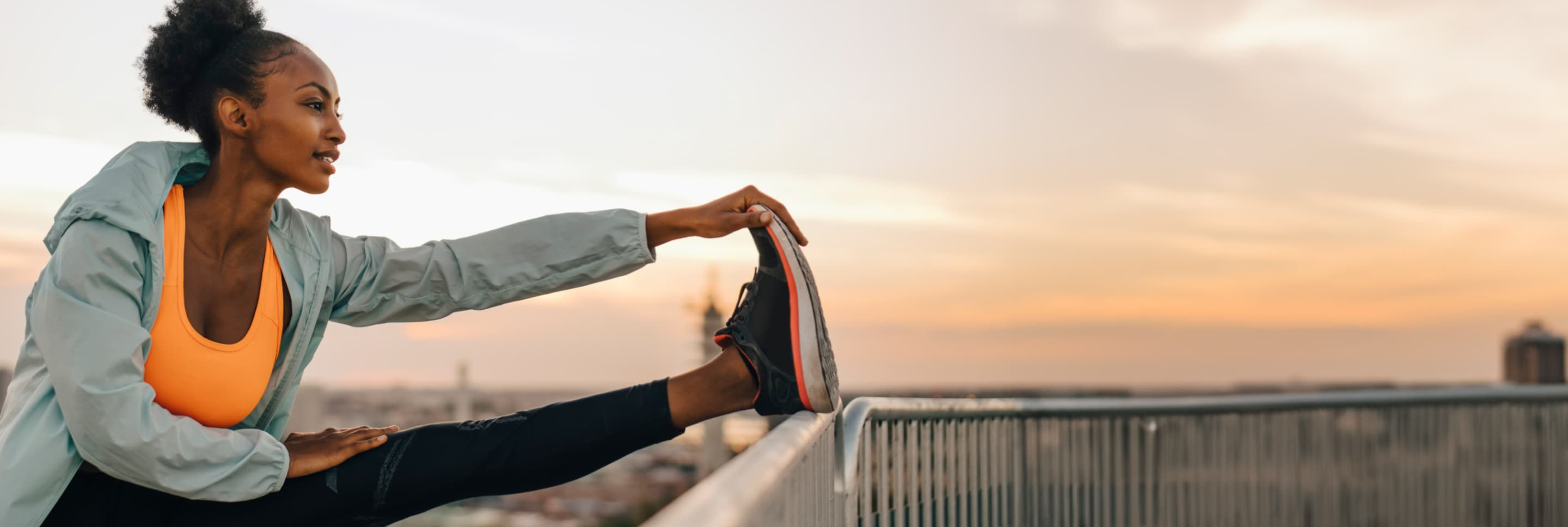 Woman in athletic clothes stretching her leg on a railing